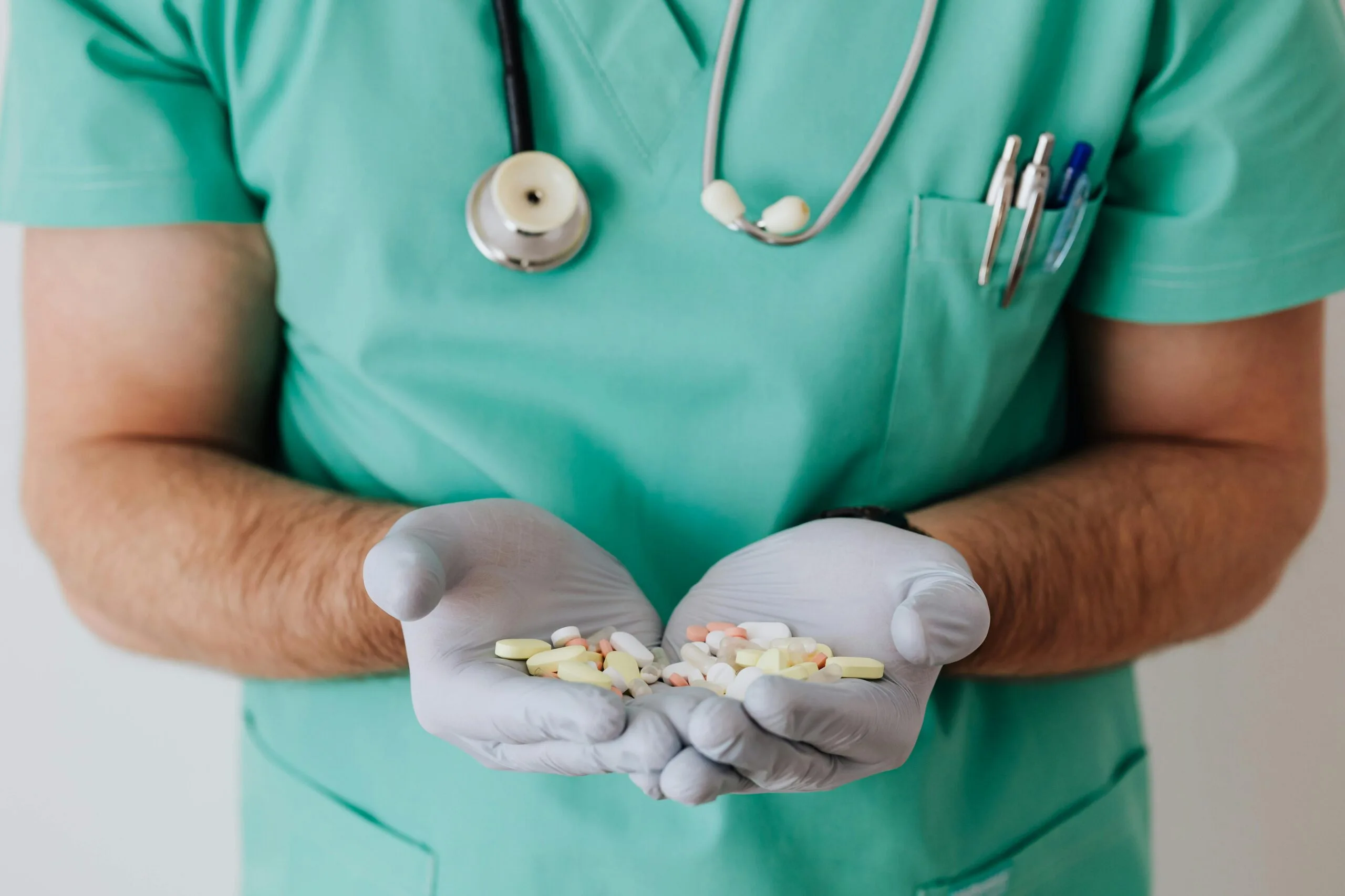 pexels-photo-4021811-4021811 A healthcare professional in uniform holding a variety of pills in gloved hands.