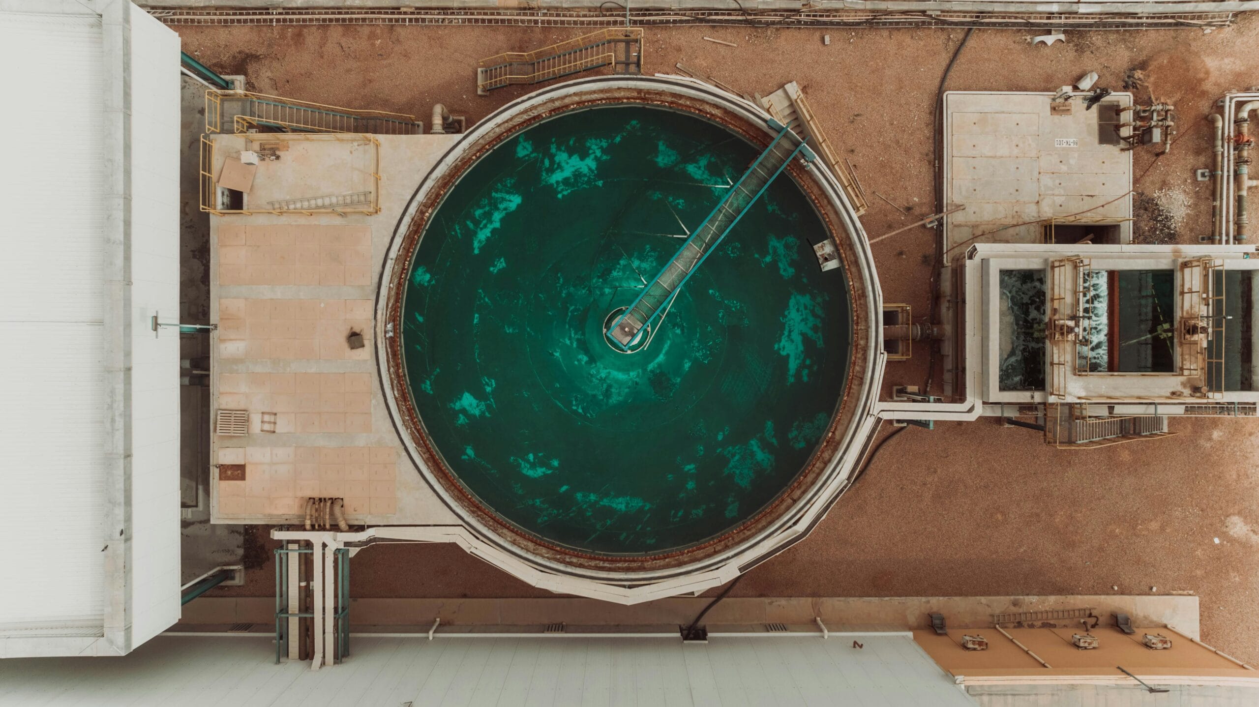 pexels-photo-24802113-24802113 Drone view of a large circular water treatment tank at an industrial facility.