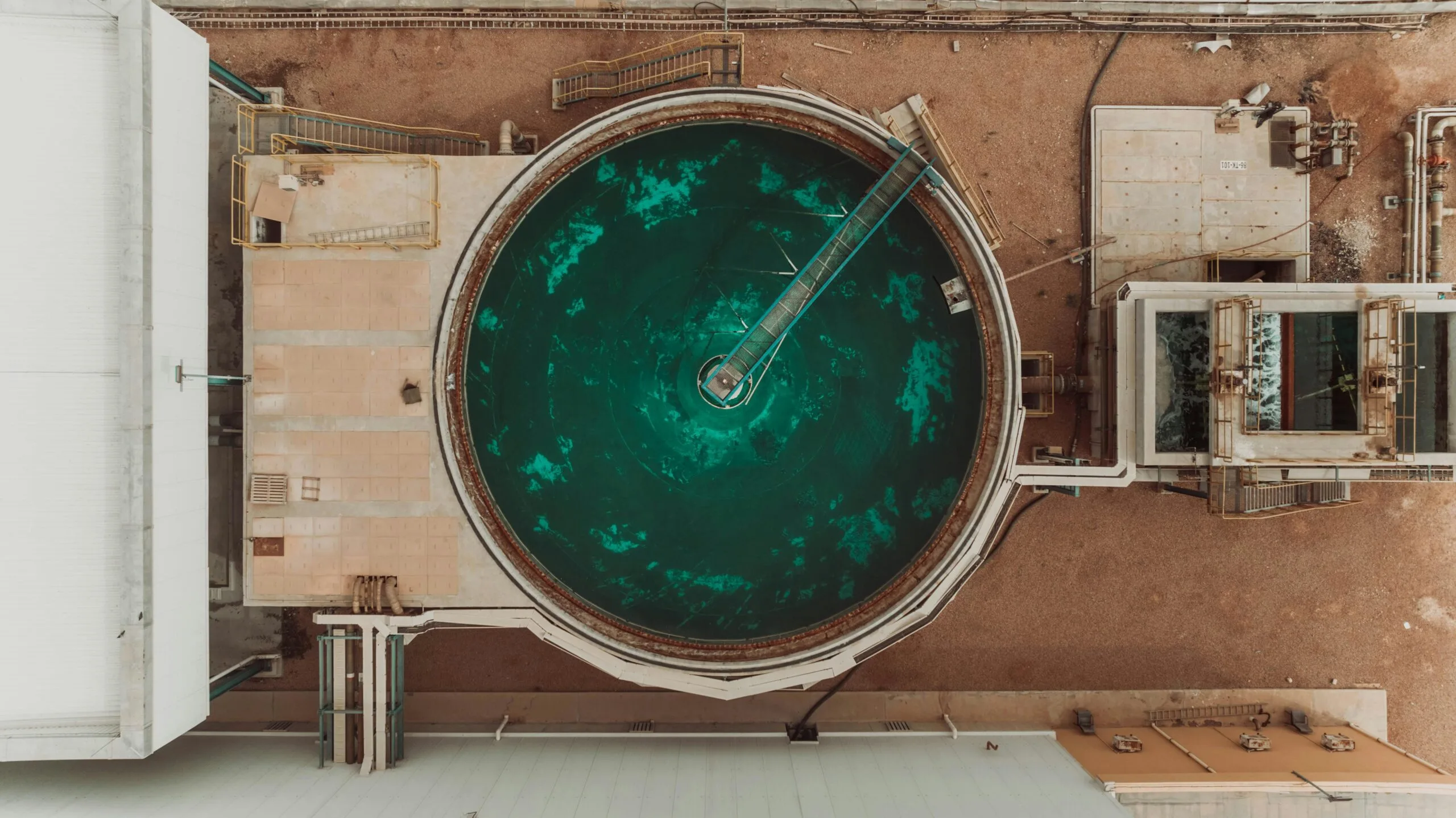 pexels-photo-24802113-24802113 Drone view of a large circular water treatment tank at an industrial facility.